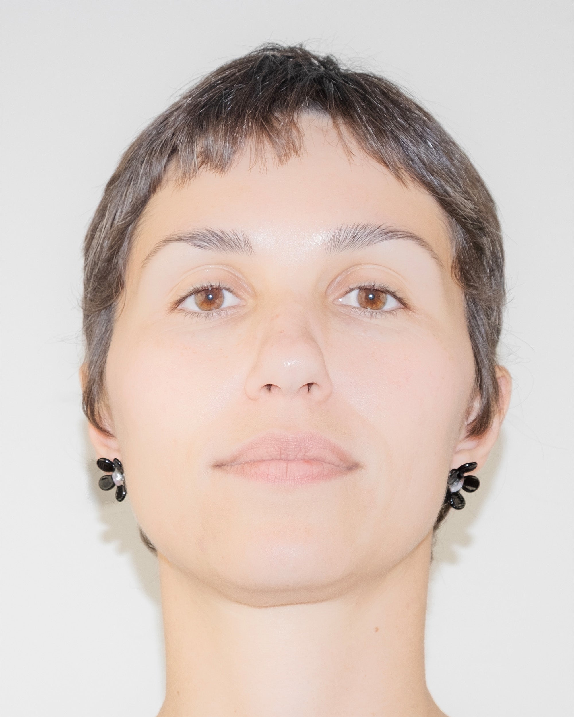 Model wearing Black Flower Stud Earrings, handmade borosilicate glass flower design on sterling silver studs.