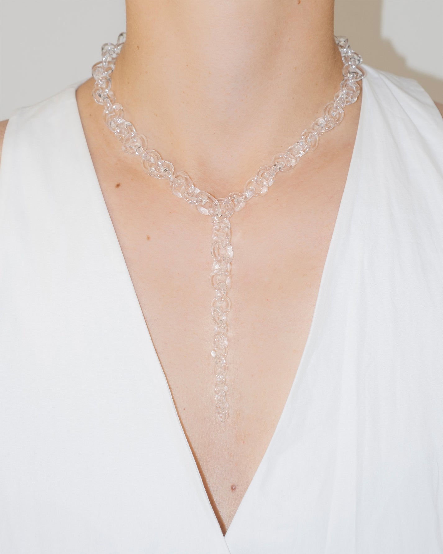 Model wearing bold transparent glass chain necklace with drop detail, handmade borosilicate links and sterling silver clasp.