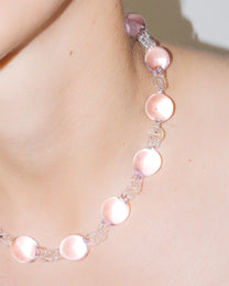 Model wearing pink Orb Necklace with transparent glass links connecting solid glass spheres, handmade borosilicate jewelry.