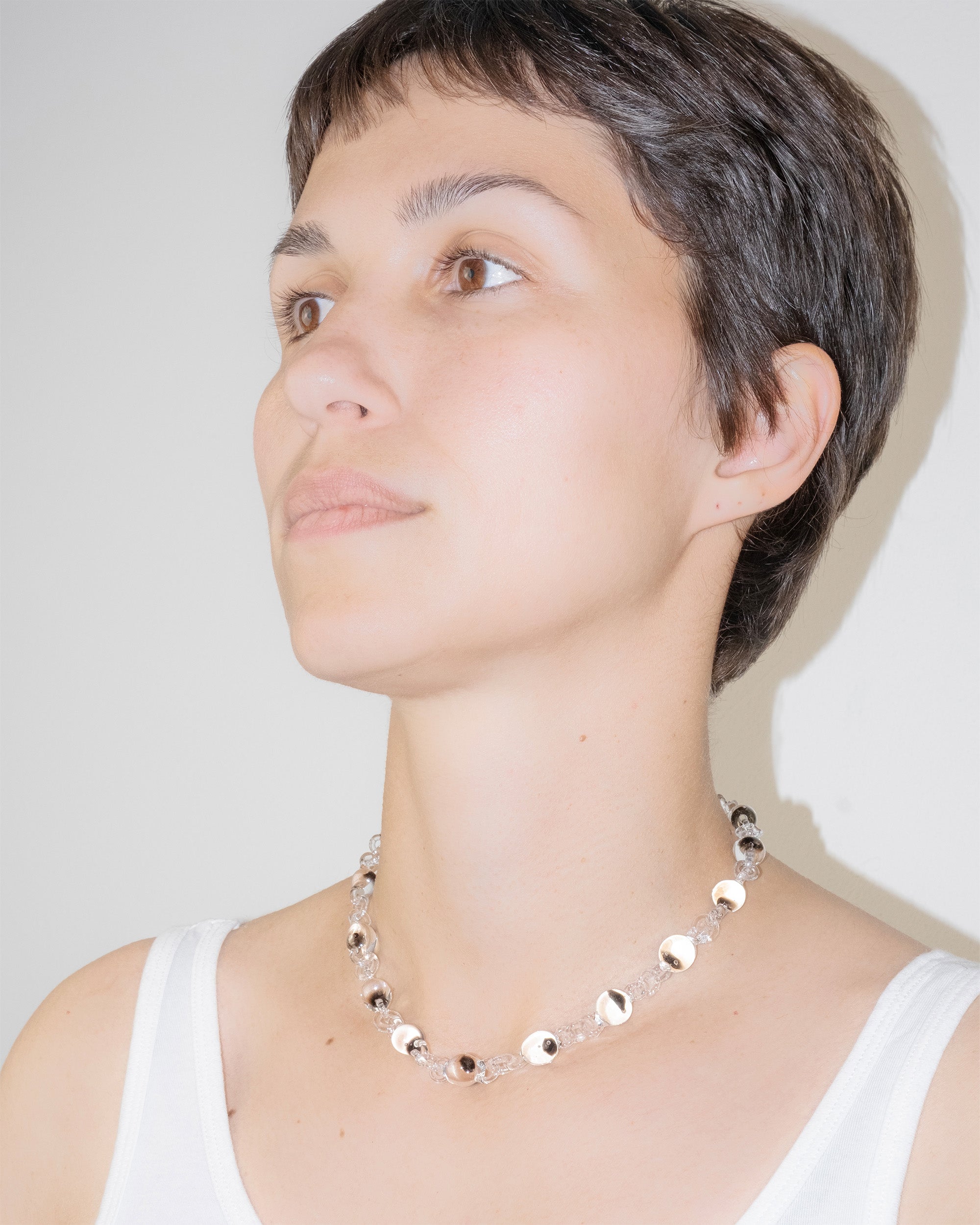 Model wearing Orb Mini Necklace with transparent glass spheres containing black-tinted fading accents, handmade borosilicate jewelry.