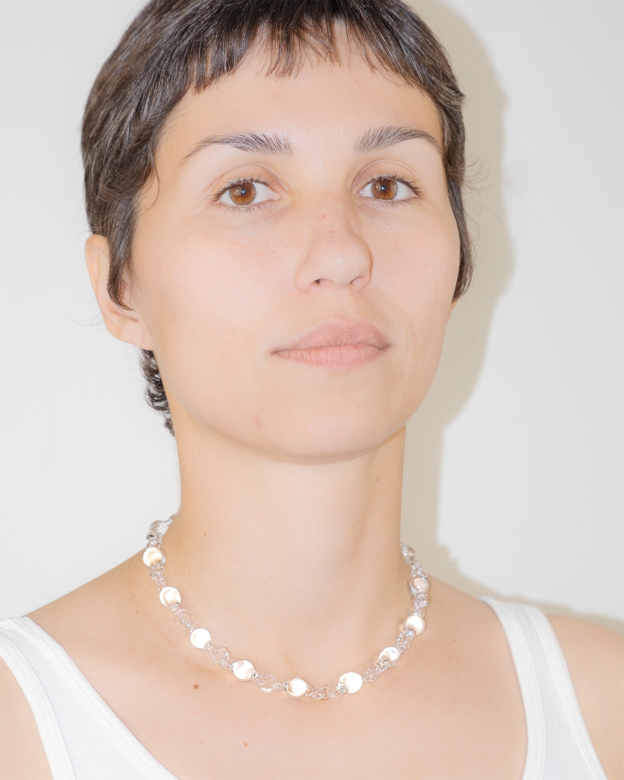 Model wearing transparent Orb Mini Necklace, handmade from smaller solid borosilicate glass spheres in a continuous chain.