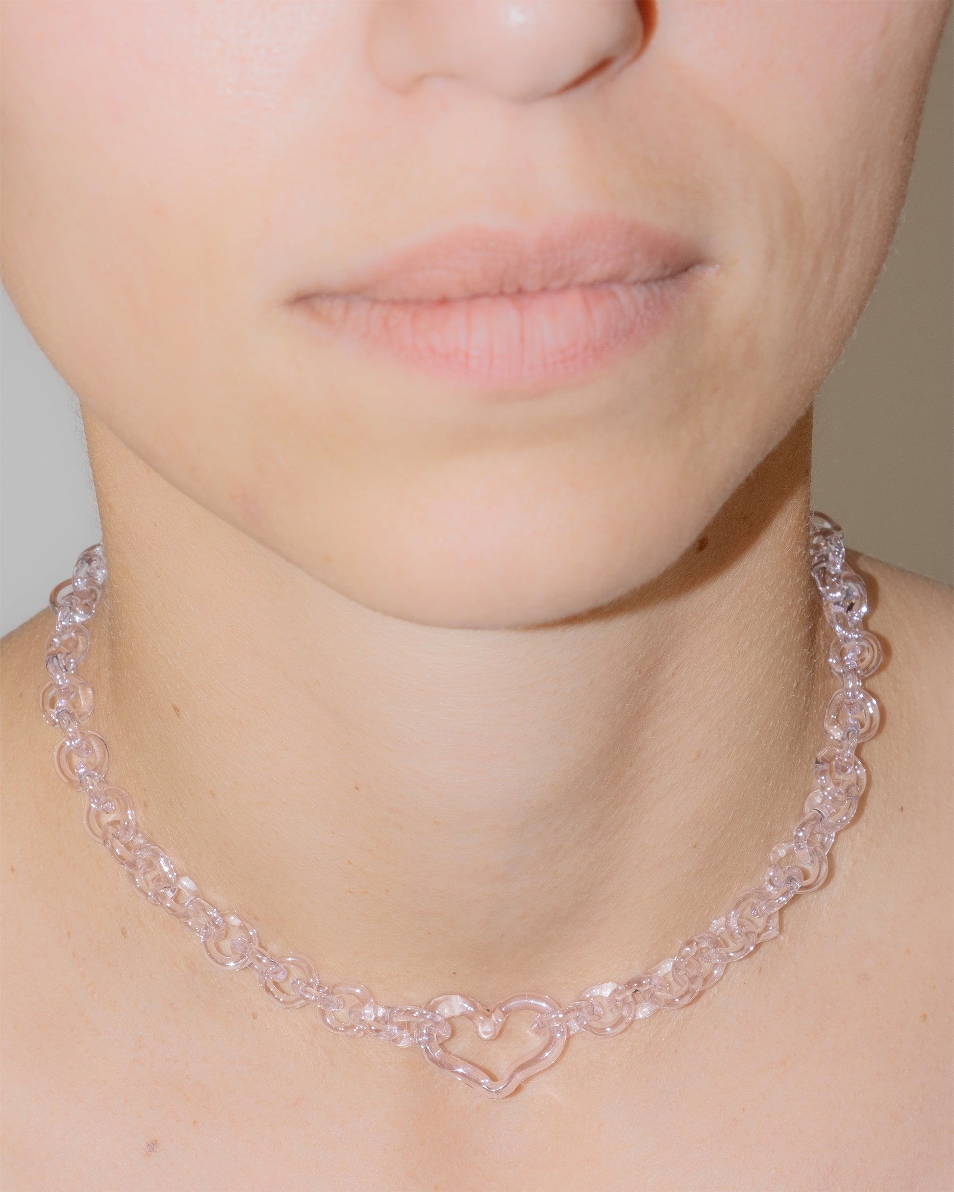 Model wearing pink thin glass chain necklace with central glass heart, handmade borosilicate jewelry, adjustable design.