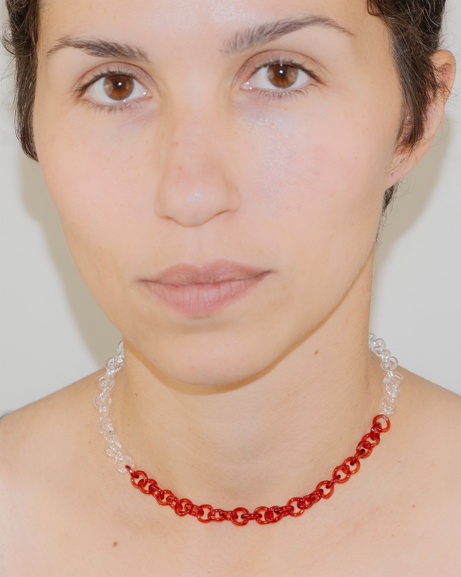 Model wearing two-tone transparent and red glass chain necklace styled as a choker, handmade thin borosilicate links with sterling silver clasp.