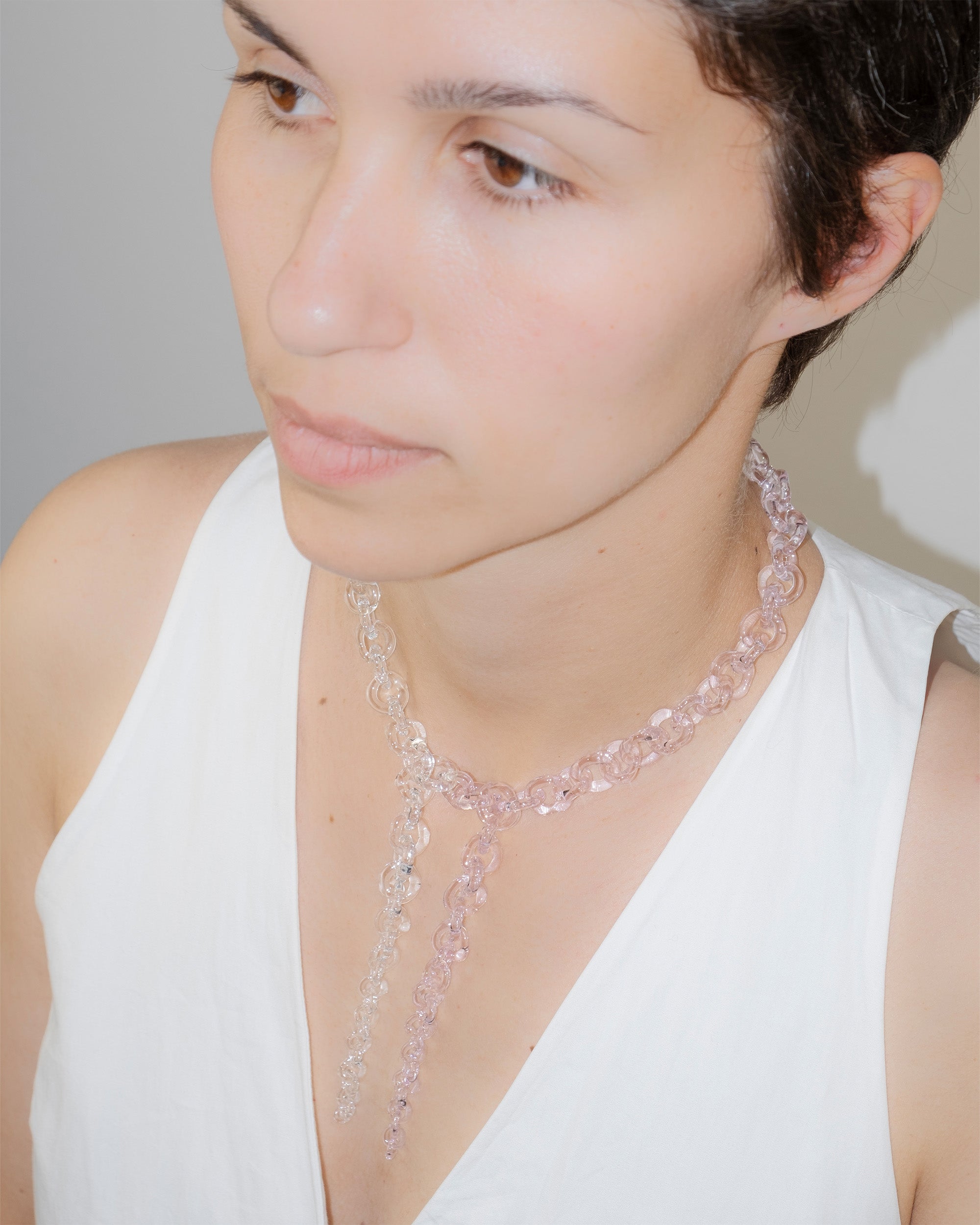 Model wearing bold transparent and pink glass chain necklace with two drop details, handmade borosilicate links and sterling silver clasp.