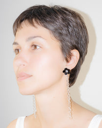 Model wearing Black Flowered Chain Earrings, handmade borosilicate glass flower with thin glass chain and silver studs.