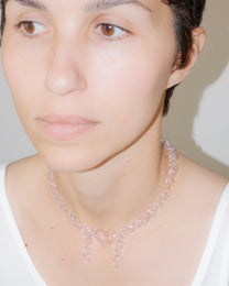 Model wearing pink thin glass chain necklace with central heart and two short side glass chains, handmade borosilicate jewelry.