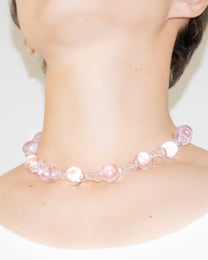 Model wearing pink Orb Necklace with transparent glass links connecting solid glass spheres, handmade borosilicate jewelry.