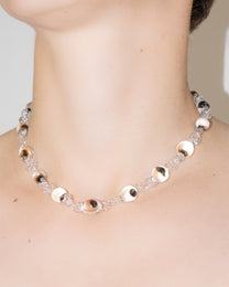 Model wearing Orb Mini Necklace with transparent glass spheres containing black-tinted fading accents, handmade borosilicate jewelry.