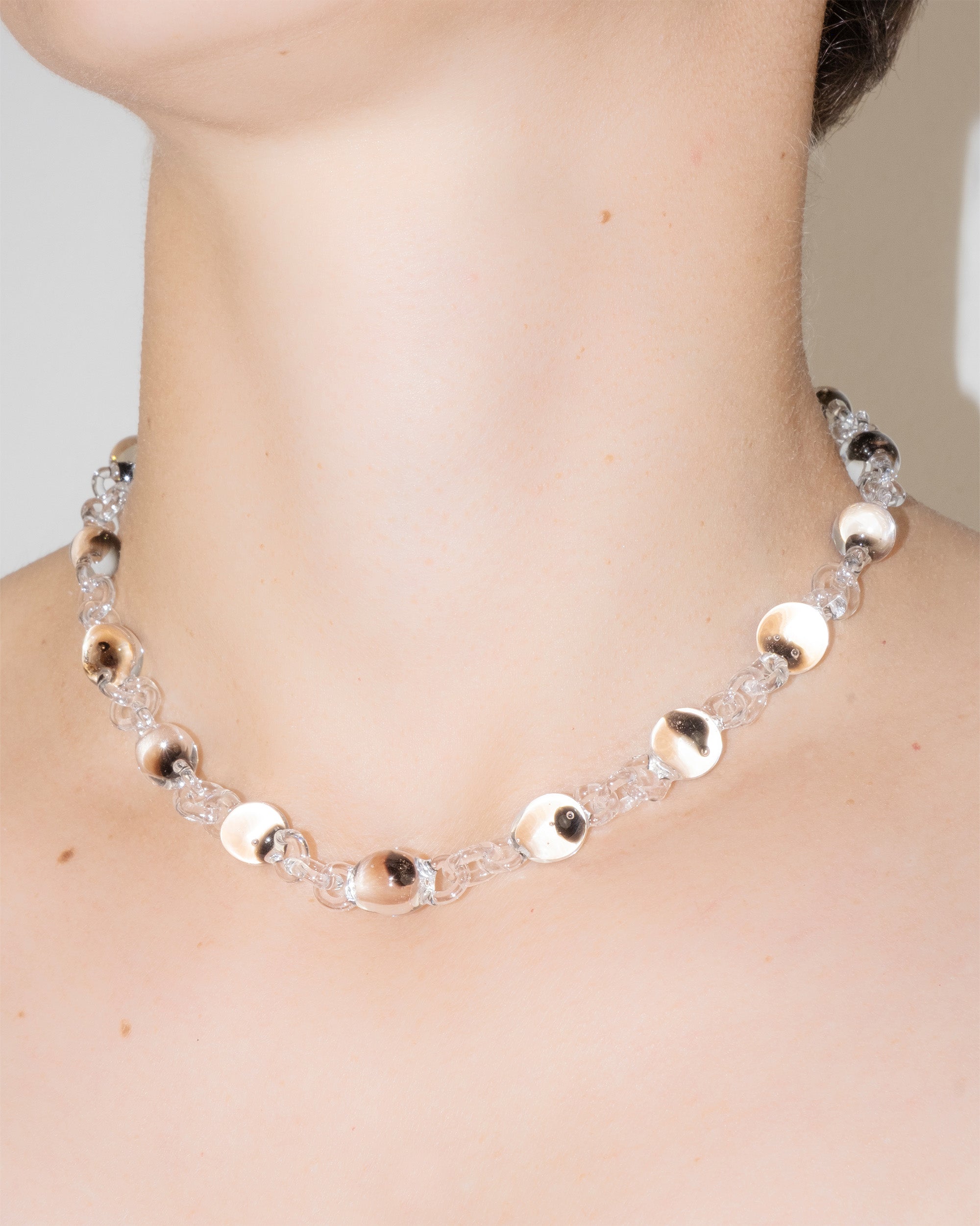 Model wearing Orb Mini Necklace with transparent glass spheres containing black-tinted fading accents, handmade borosilicate jewelry.