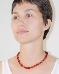 Model wearing red Orb Mini Necklace with smaller solid borosilicate glass spheres linked in a delicate continuous chain.