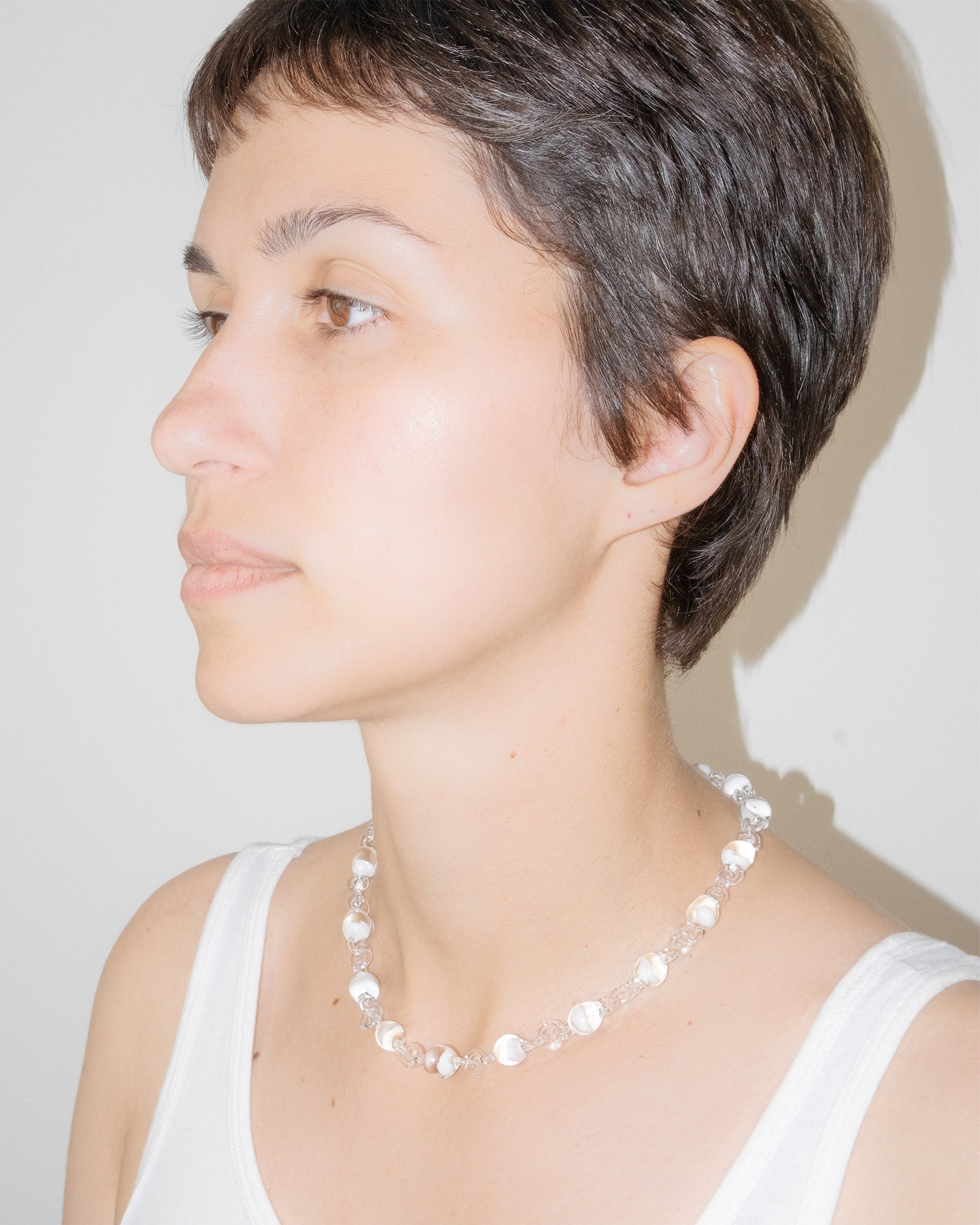 Model wearing Orb Mini Necklace with transparent glass spheres containing white-tinted fading accents, handmade borosilicate jewelry.