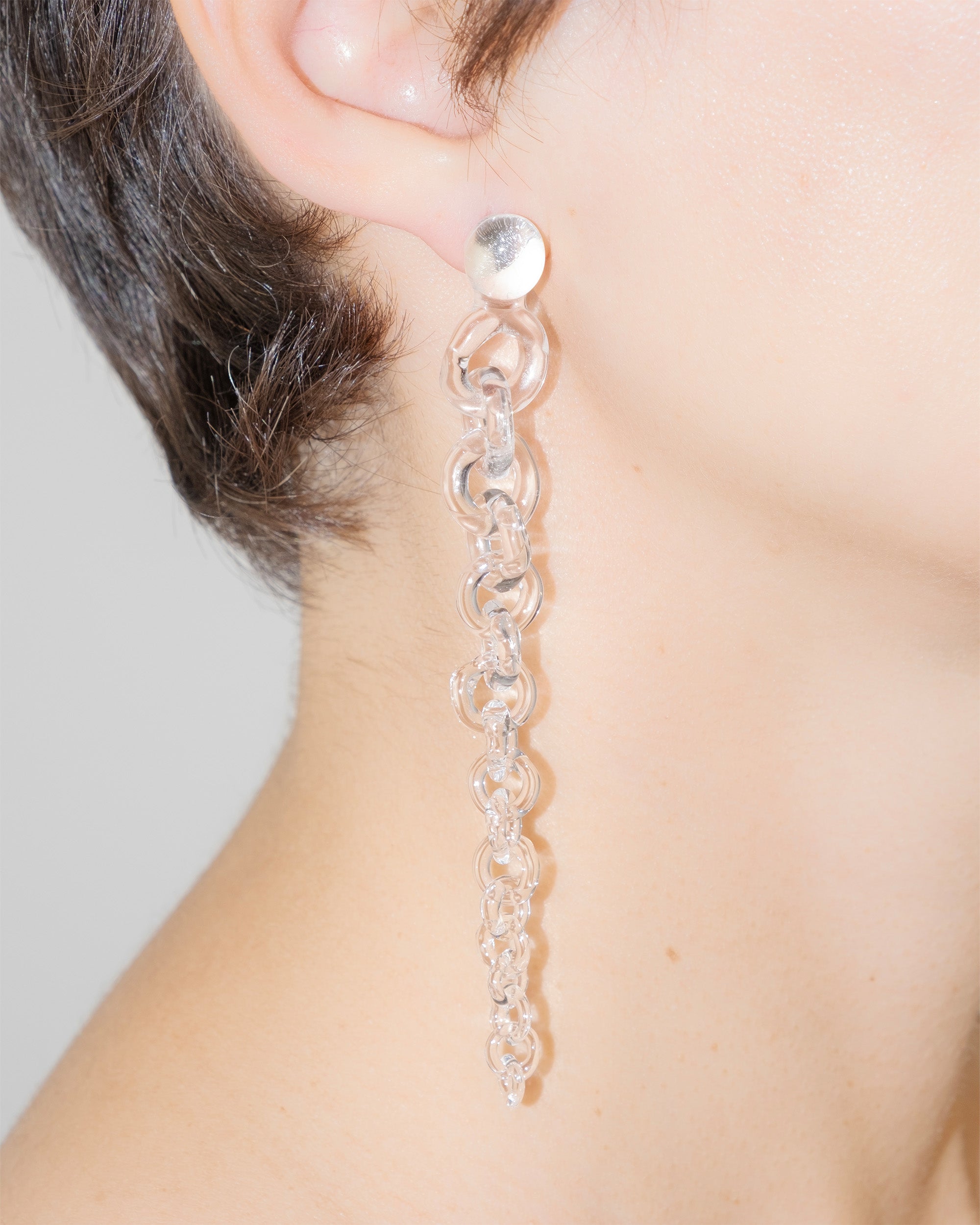 Model wearing Tapered Drop Earrings, handmade borosilicate glass tapering from thick to thin with orb-like top detail and sterling silver studs.