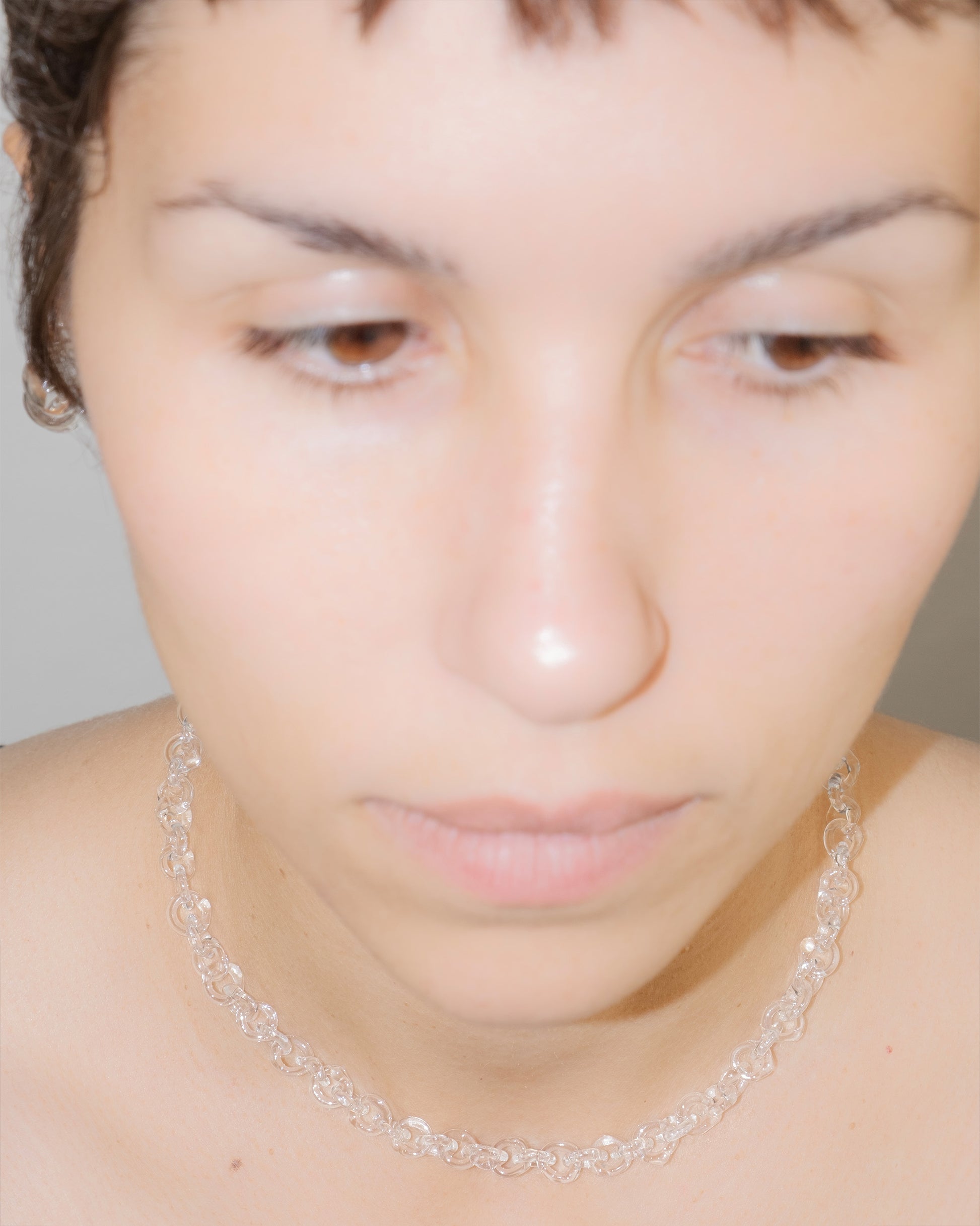 Model wearing thin transparent glass chain necklace styled as a choker, handmade with sterling silver clasp.
