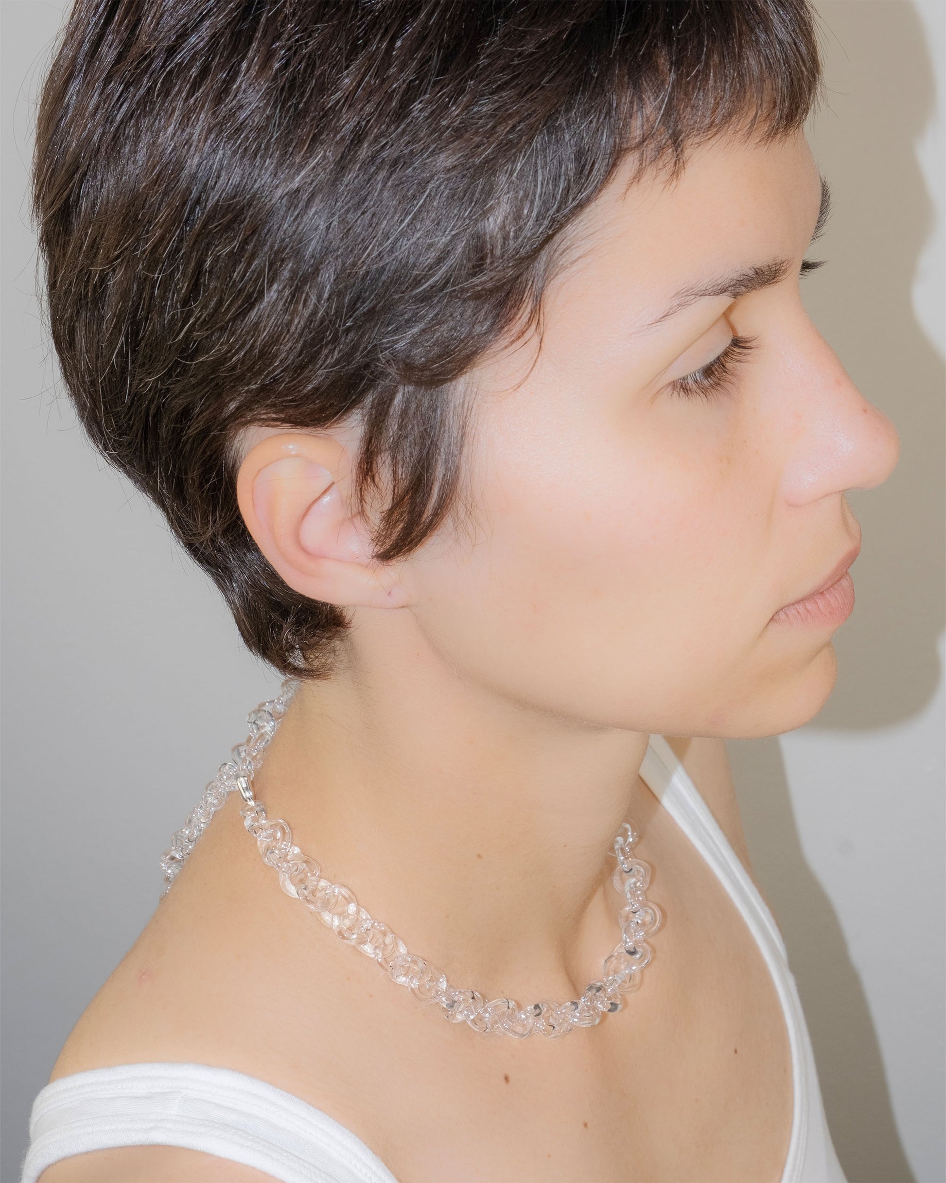 Model wearing bold glass chain necklace with thick borosilicate links, minimal handmade design, and sterling silver clasp.