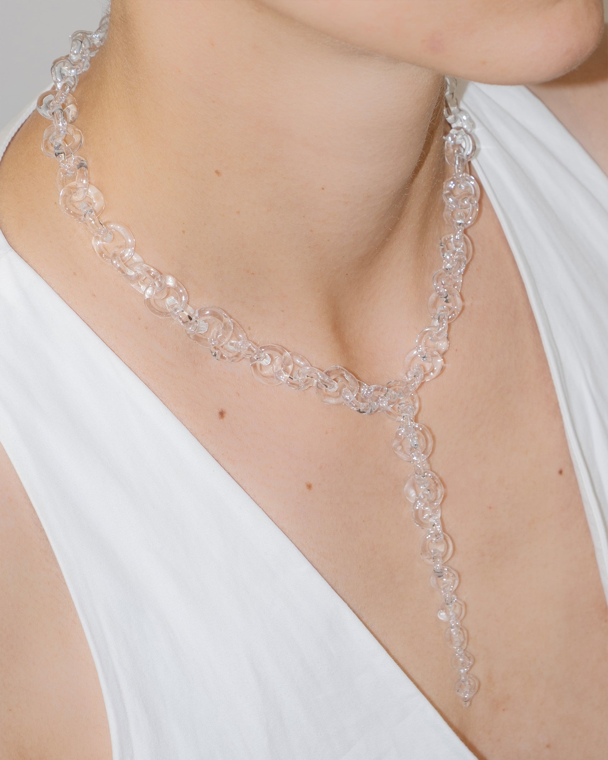 Model wearing bold transparent glass chain necklace with drop detail, handmade borosilicate links and sterling silver clasp.
