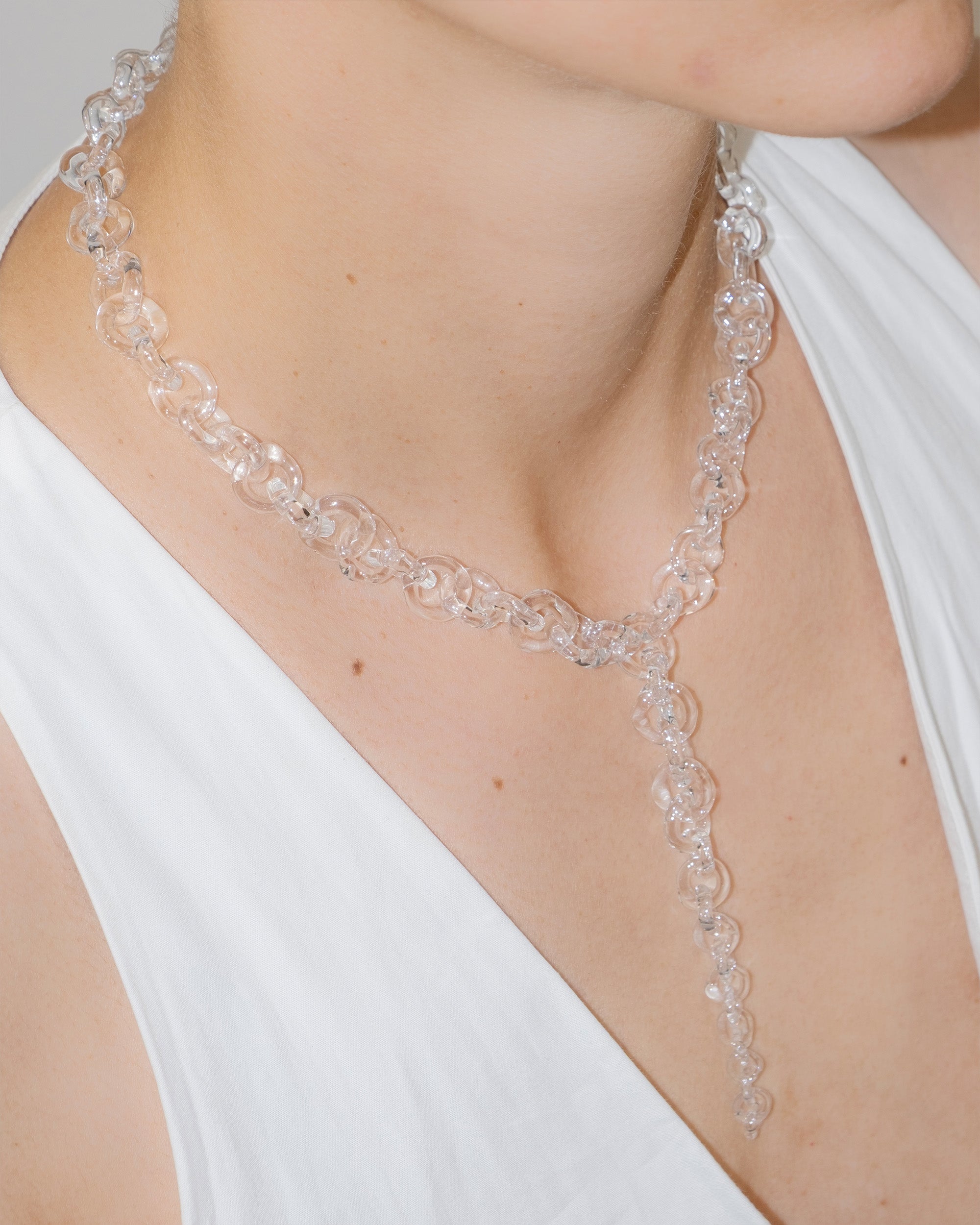 Model wearing bold transparent glass chain necklace with drop detail, handmade borosilicate links and sterling silver clasp.
