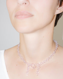 Model wearing pink thin glass chain necklace with central heart and two short side glass chains, handmade borosilicate jewelry.