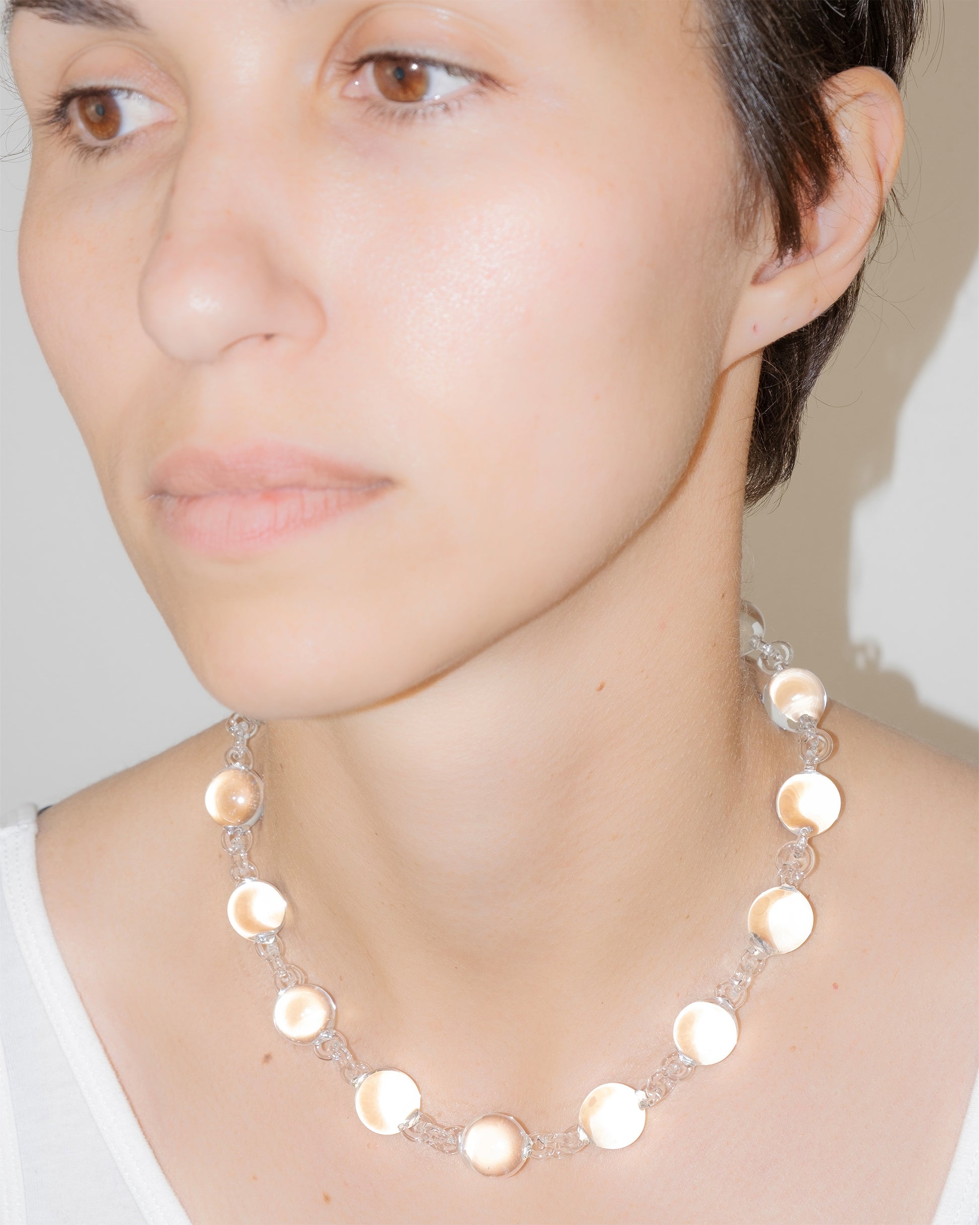 Model wearing transparent Orb Necklace, handmade solid borosilicate glass spheres linked in a continuous glass chain.