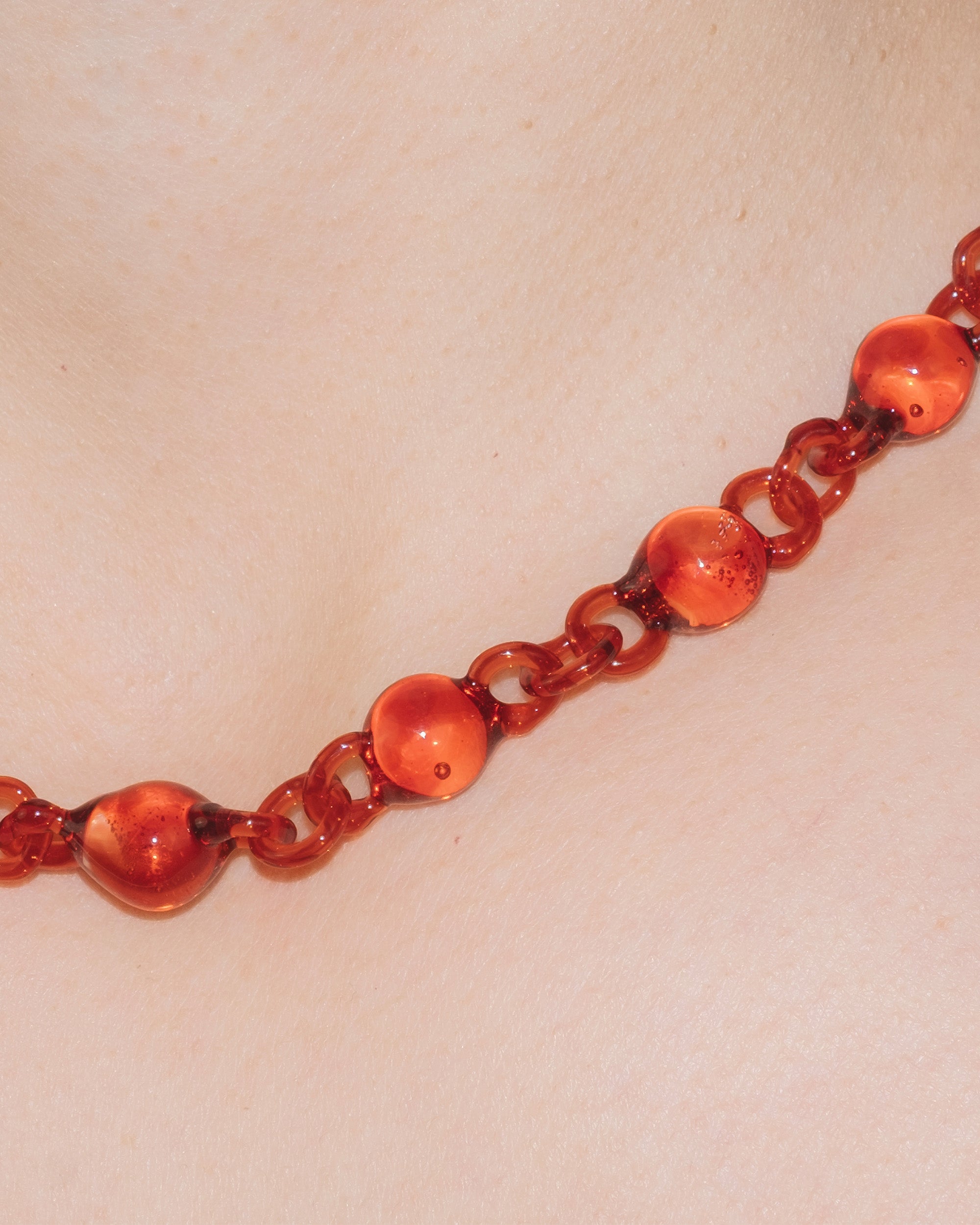 Model wearing red Orb Mini Necklace with smaller solid borosilicate glass spheres linked in a delicate continuous chain.