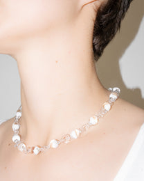 Model wearing Orb Mini Necklace with transparent glass spheres containing white-tinted fading accents, handmade borosilicate jewelry.