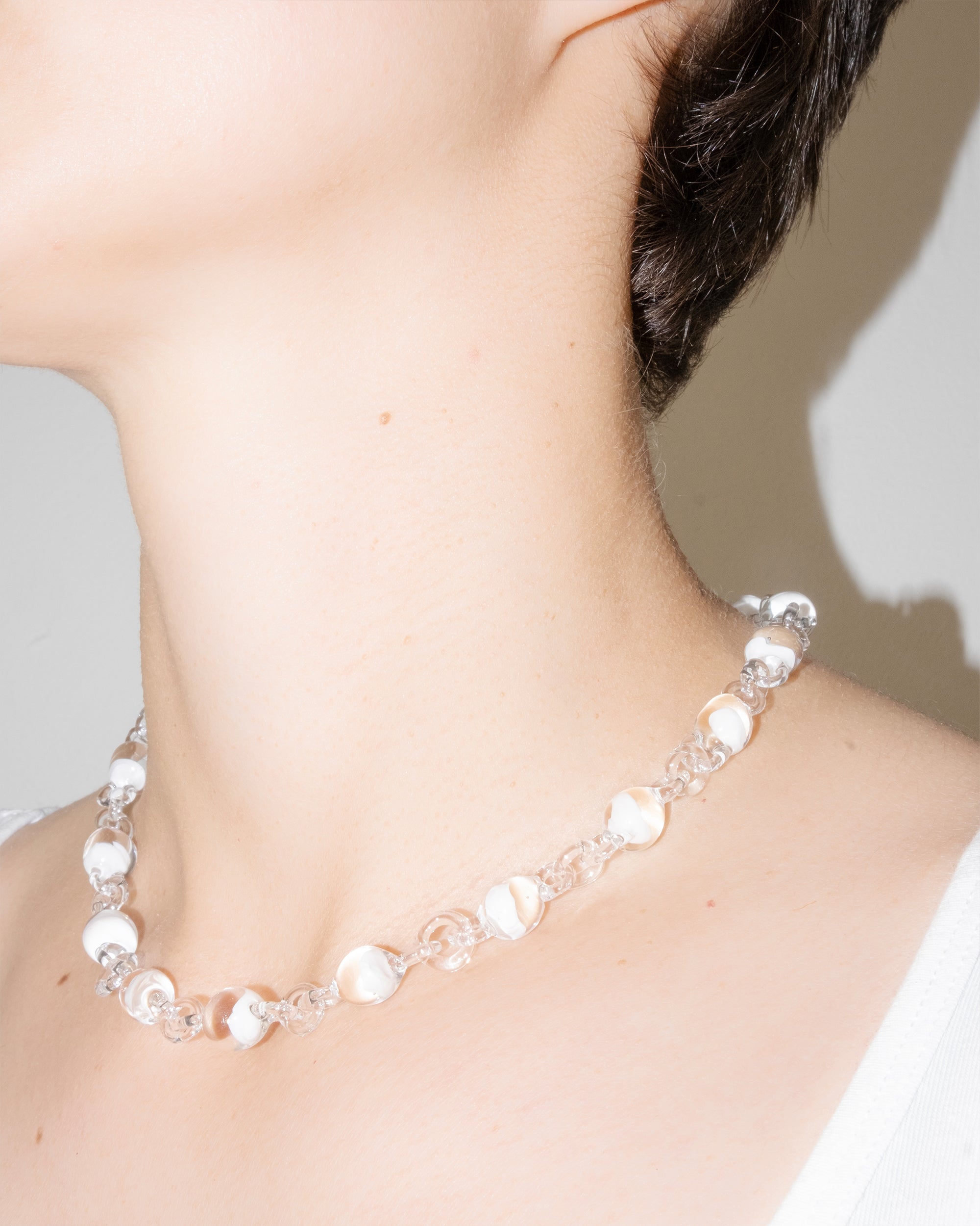 Model wearing Orb Mini Necklace with transparent glass spheres containing white-tinted fading accents, handmade borosilicate jewelry.