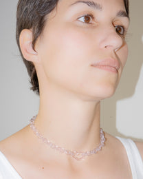 Model wearing pink thin glass chain necklace with central glass heart, handmade borosilicate jewelry, adjustable design.