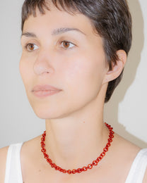 Model wearing thin red glass chain necklace styled as a choker, handmade borosilicate links with sterling silver clasp.