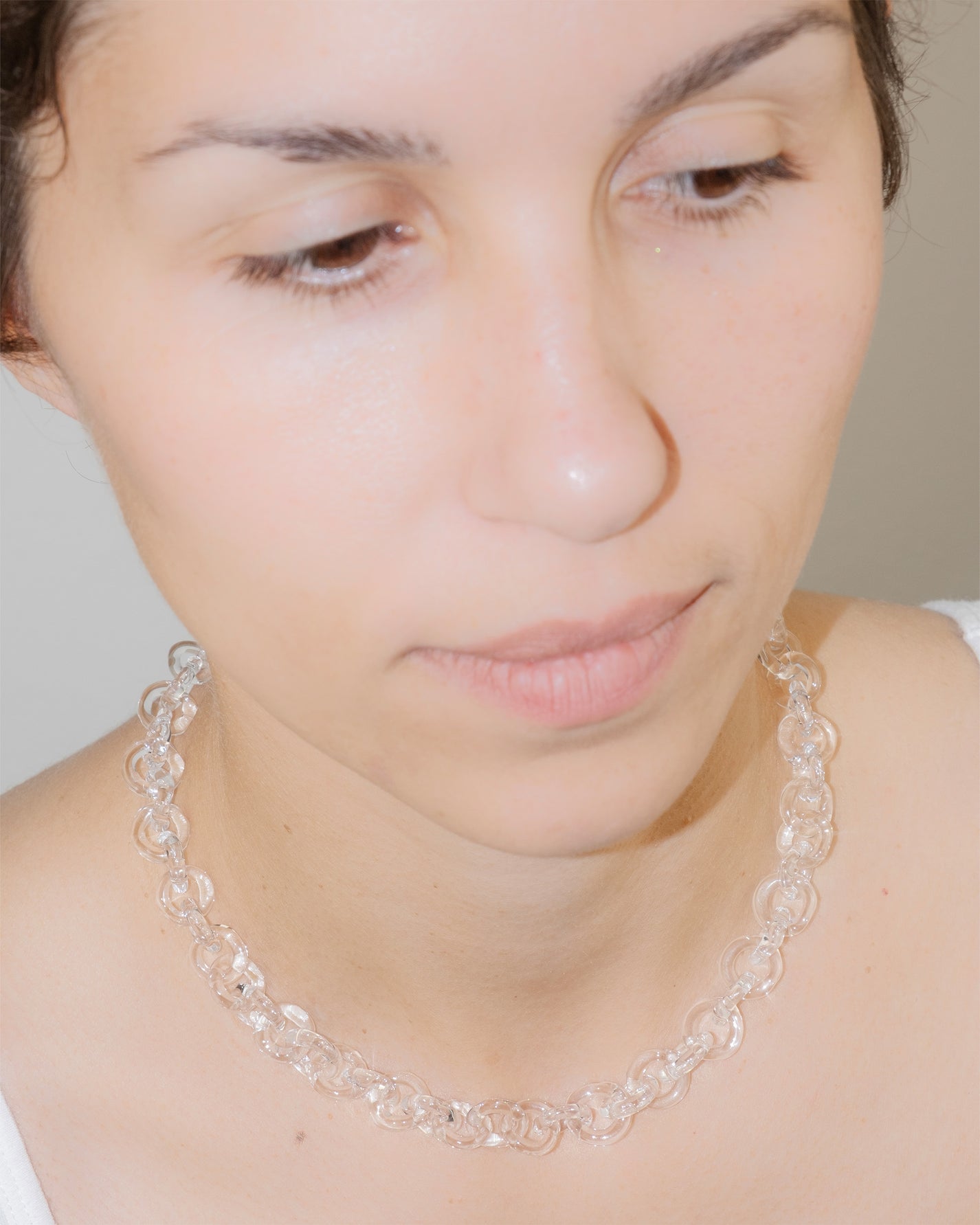 Model wearing bold glass chain necklace with thick borosilicate links, minimal handmade design, and sterling silver clasp.