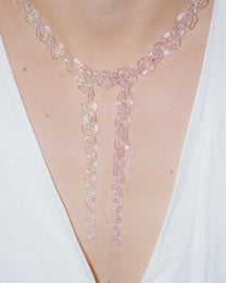 Model wearing bold transparent and pink glass chain necklace with two drop details, handmade borosilicate links and sterling silver clasp.