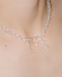 Model wearing transparent thin glass chain necklace with glass heart and two short side glass chains, handmade borosilicate jewelry.