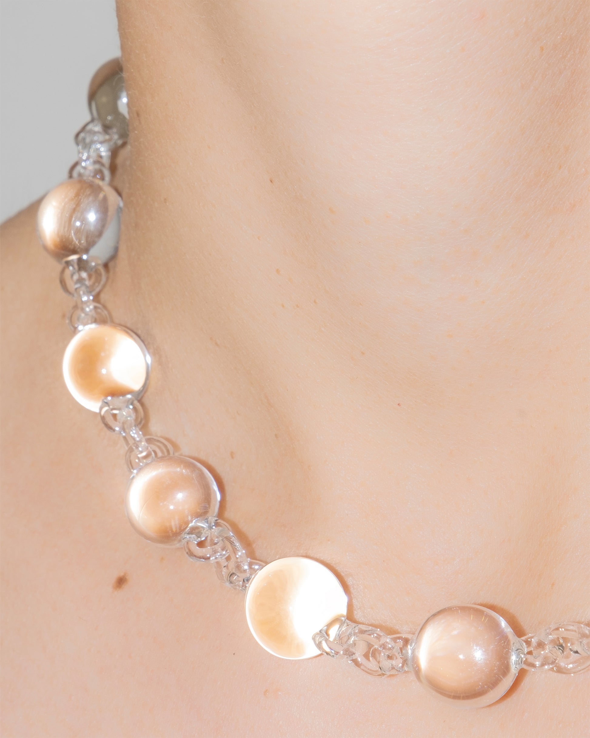 Model wearing transparent Orb Necklace, handmade solid borosilicate glass spheres linked in a continuous glass chain.