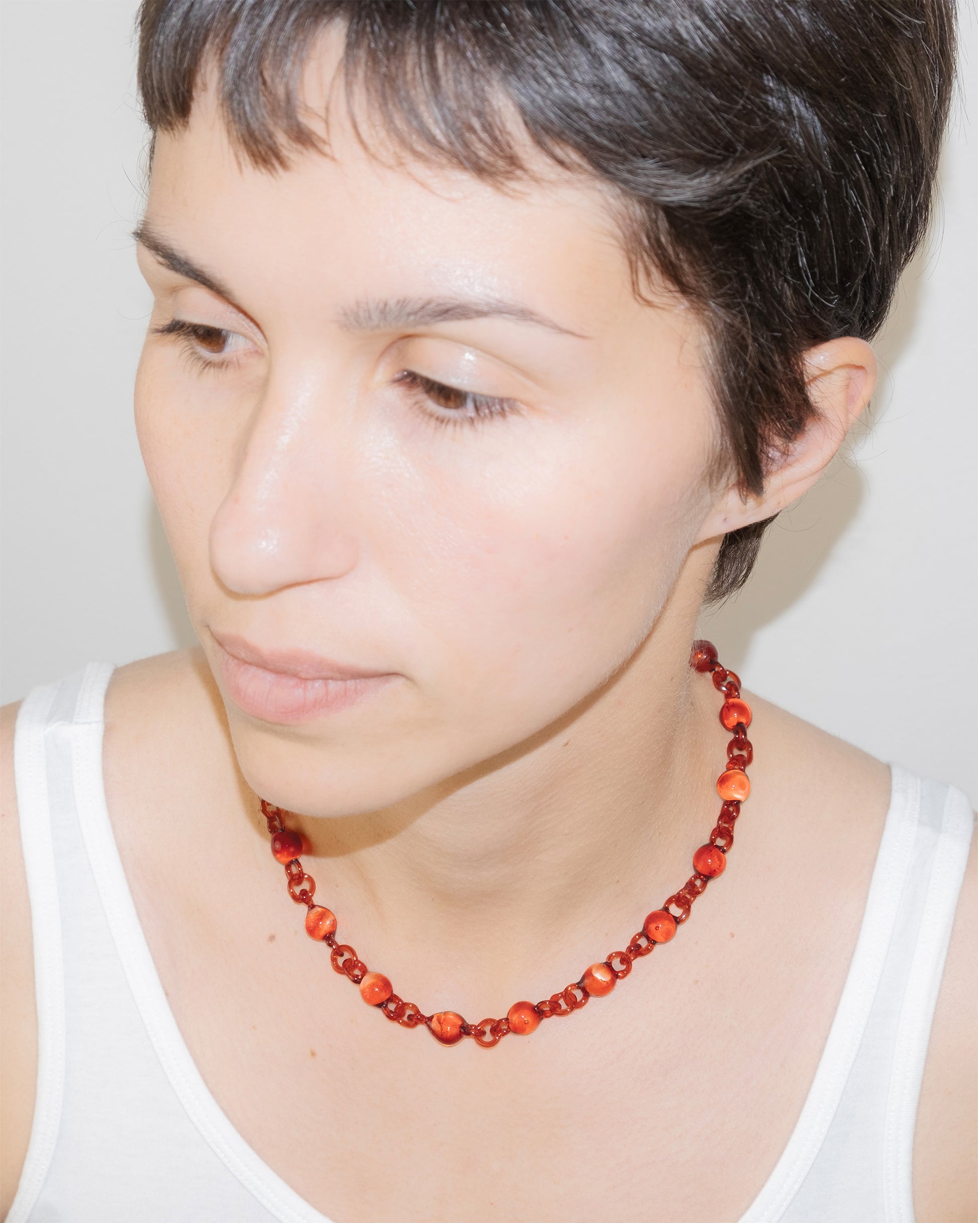 Model wearing red Orb Mini Necklace with smaller solid borosilicate glass spheres linked in a delicate continuous chain.