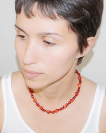 Model wearing red Orb Mini Necklace with smaller solid borosilicate glass spheres linked in a delicate continuous chain.