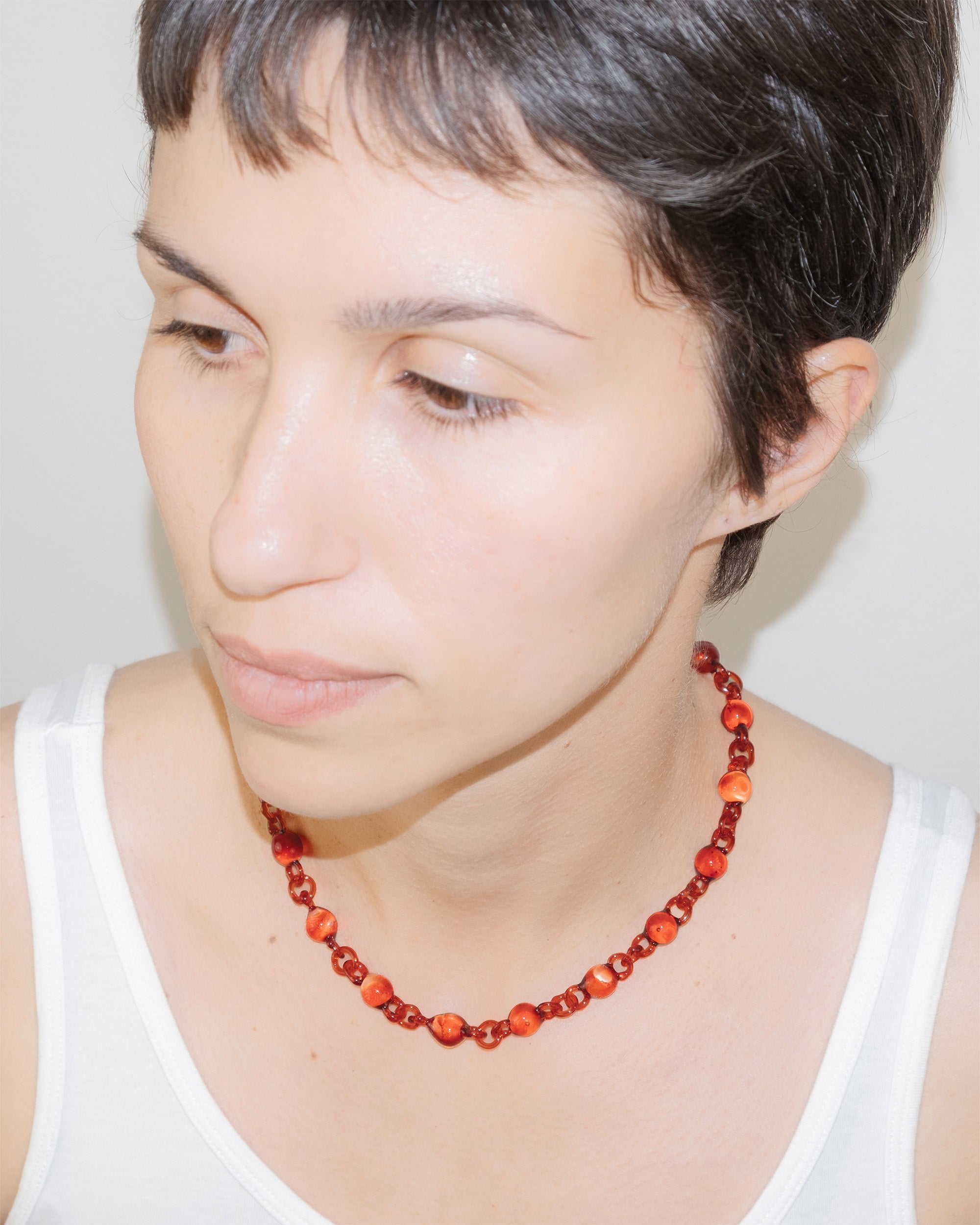 Model wearing red Orb Mini Necklace with smaller solid borosilicate glass spheres linked in a delicate continuous chain.