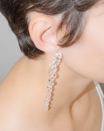 Model wearing Tapered Drop Earrings, handmade borosilicate glass tapering from thick to thin with orb-like top detail and sterling silver studs.