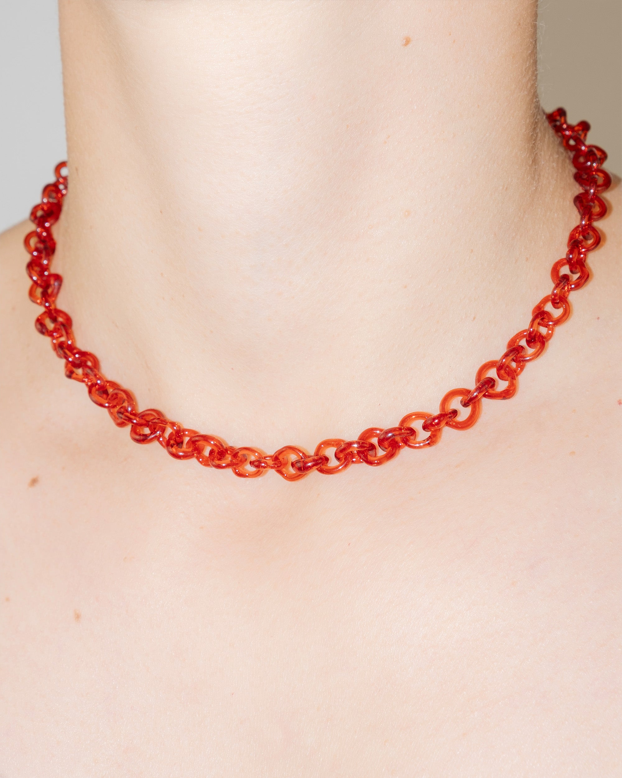 Model wearing thin red glass chain necklace styled as a choker.