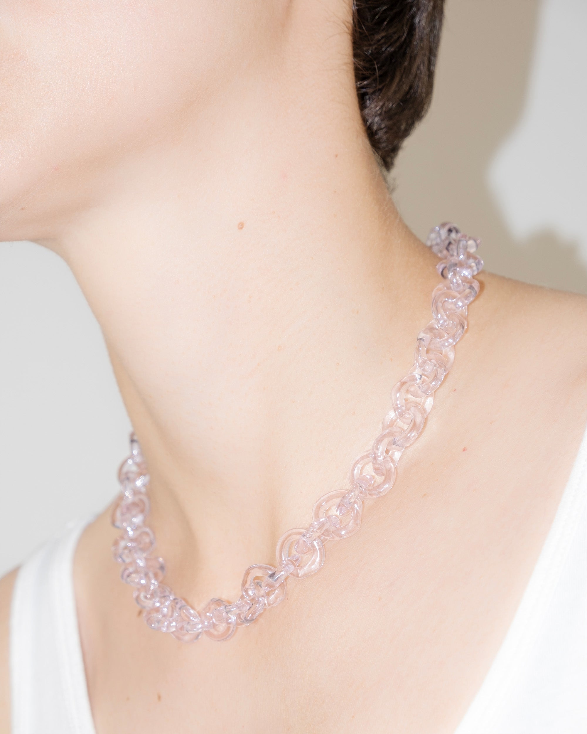 Model wearing bold glass chain necklace in pink, handmade borosilicate links with minimal, timeless design.