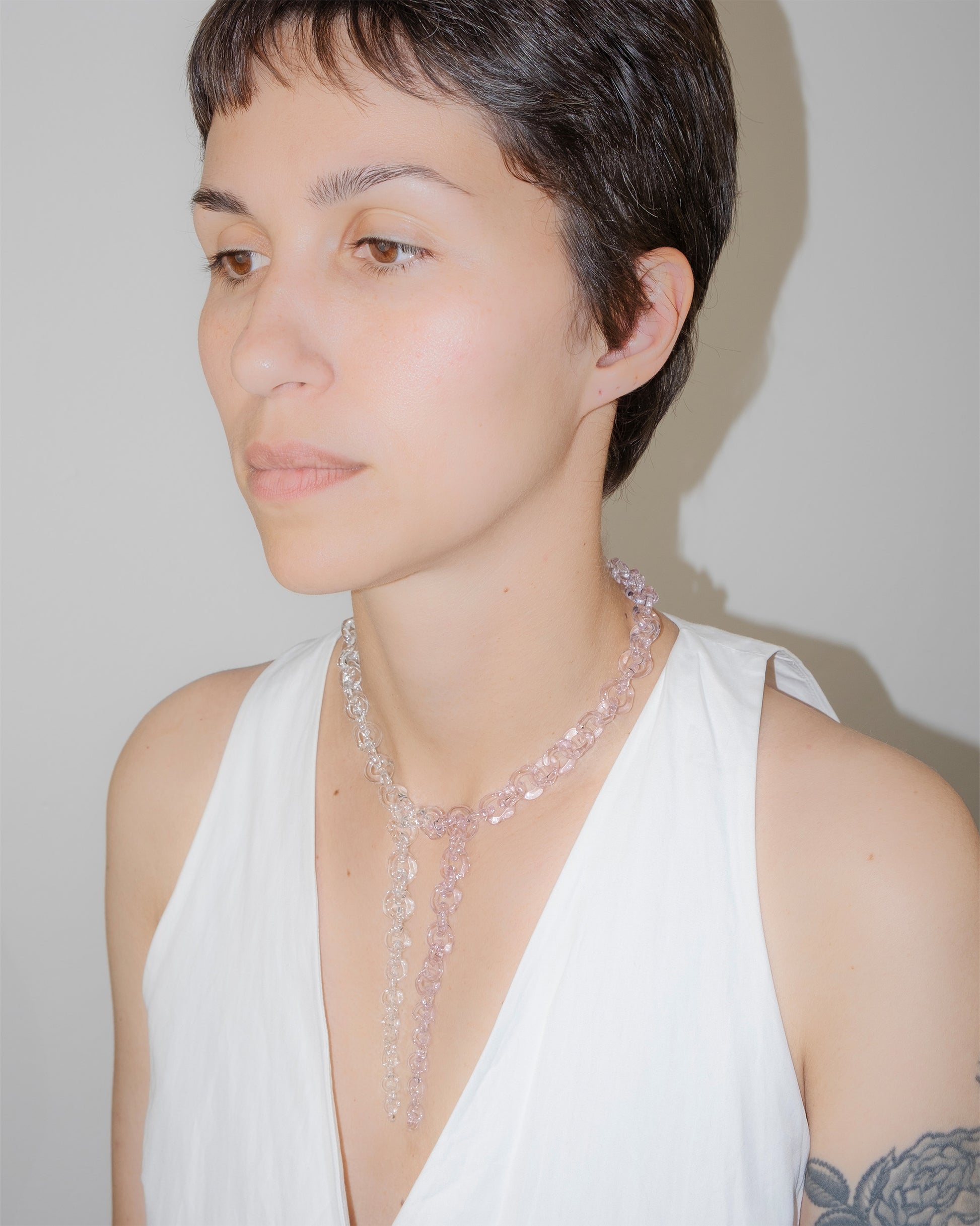 Model wearing bold transparent and pink glass chain necklace with two drop details, handmade borosilicate links and sterling silver clasp.