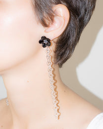 Model wearing Black Flowered Chain Earrings, handmade borosilicate glass flower with thin glass chain and silver studs.