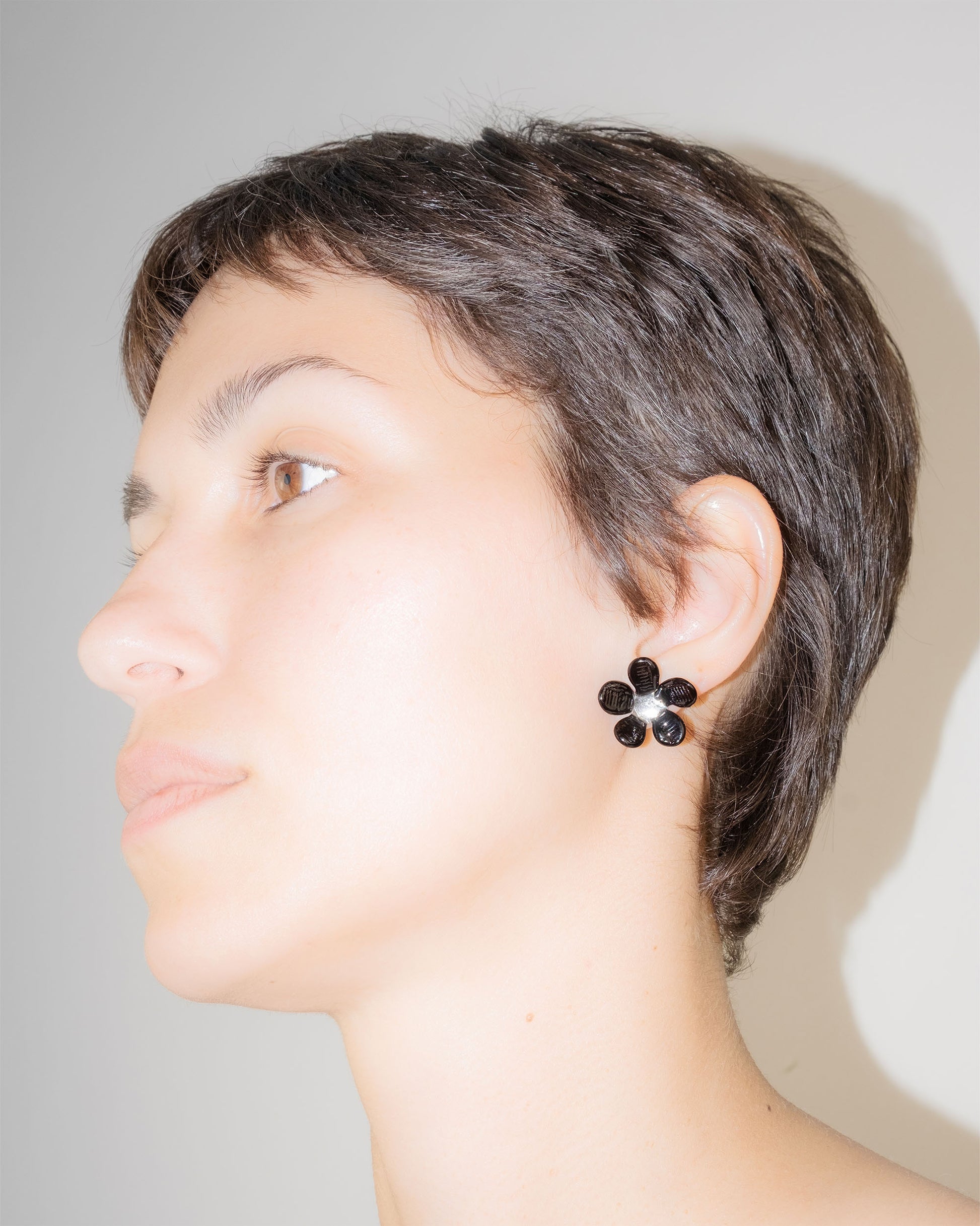 Model wearing Black Flower Stud Earrings, handmade borosilicate glass flower design on sterling silver studs.