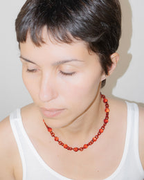 Model wearing red Orb Mini Necklace with smaller solid borosilicate glass spheres linked in a delicate continuous chain.
