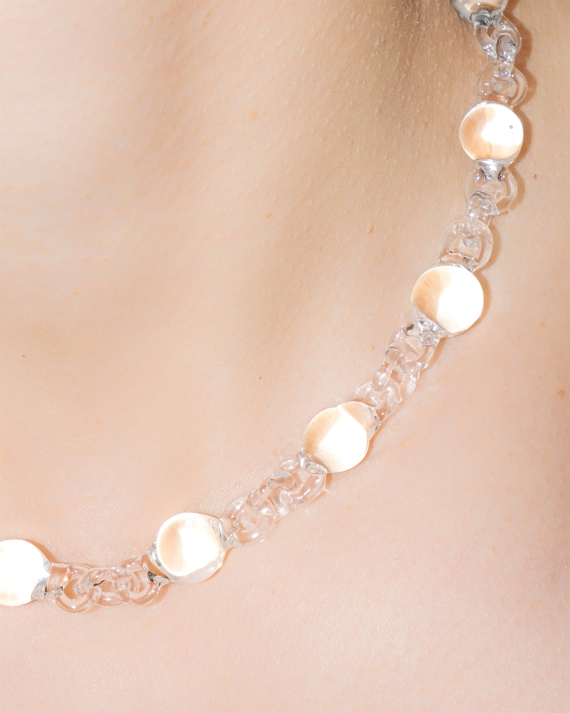 Model wearing transparent Orb Mini Necklace, handmade from smaller solid borosilicate glass spheres in a continuous chain.