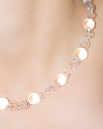 Model wearing transparent Orb Mini Necklace, handmade from smaller solid borosilicate glass spheres in a continuous chain.