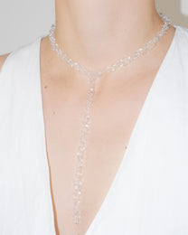Model wearing thin transparent glass chain necklace with extended drop, styled elegantly.