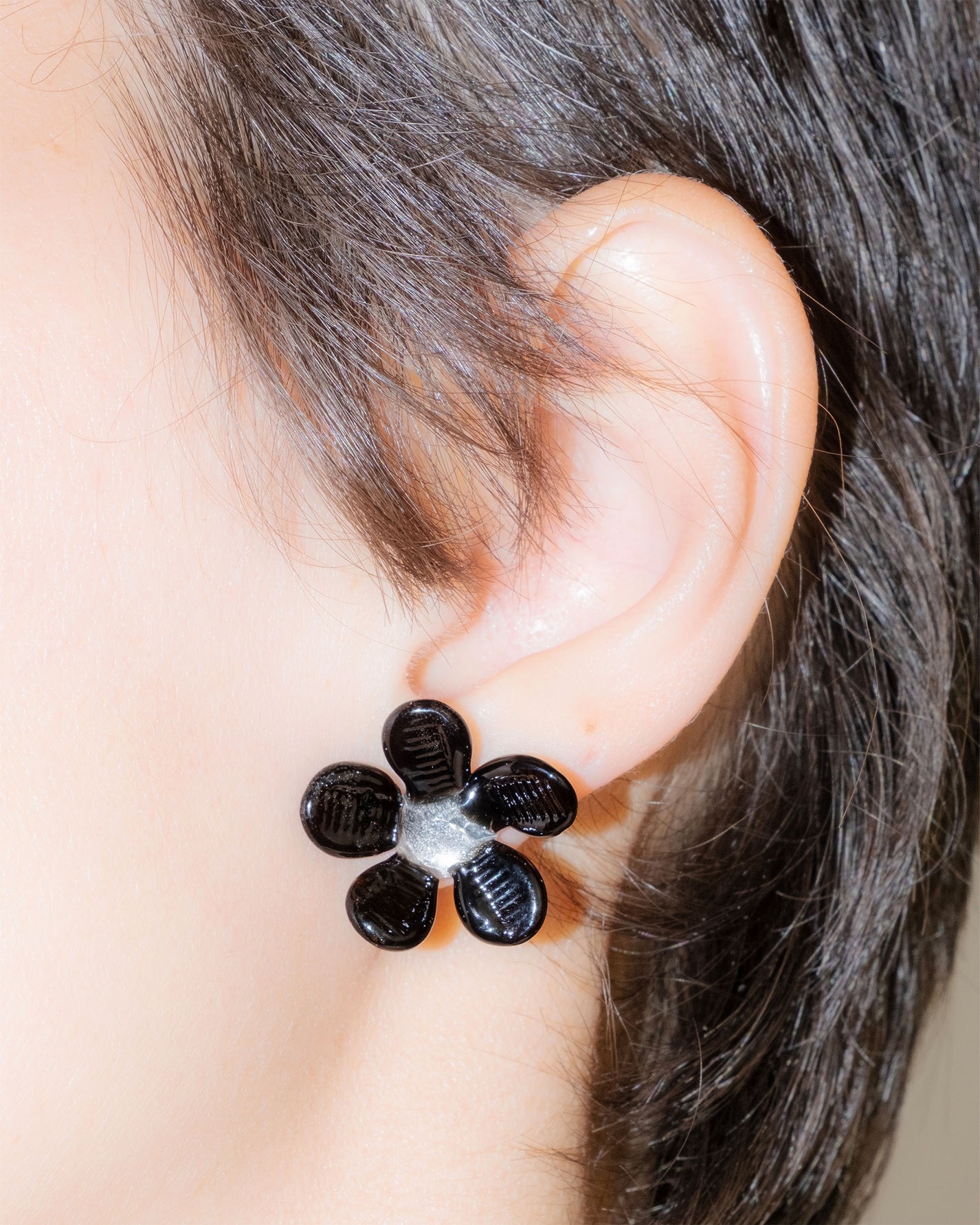 Model wearing Black Flower Stud Earrings, handmade borosilicate glass flower design on sterling silver studs.