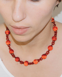 Model wearing red Orb Necklace with solid glass spheres linked into a continuous glass chain, handmade borosilicate jewelry.