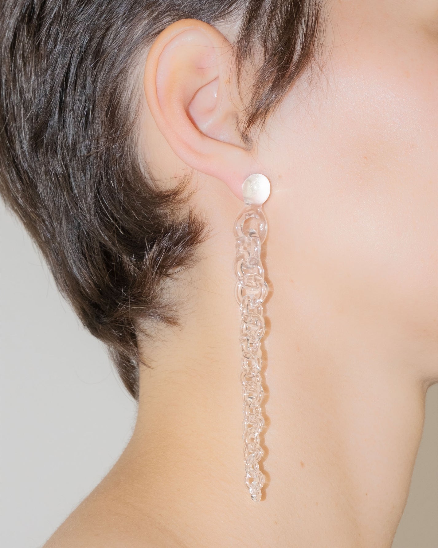 Model wearing Tapered Drop Earrings, handmade borosilicate glass tapering from thick to thin with orb-like top detail and sterling silver studs.