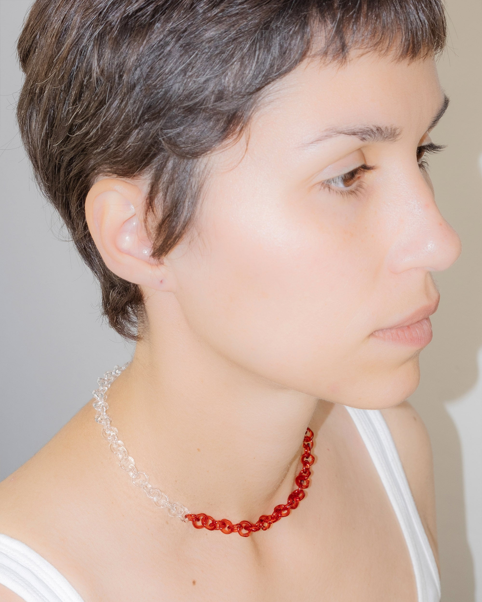 Model wearing two-tone transparent and red glass chain necklace styled as a choker, handmade thin borosilicate links with sterling silver clasp.