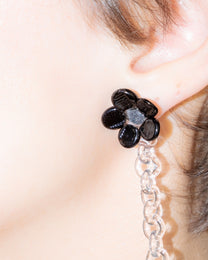 Model wearing Black Flowered Chain Earrings, handmade borosilicate glass flower with thin glass chain and silver studs.