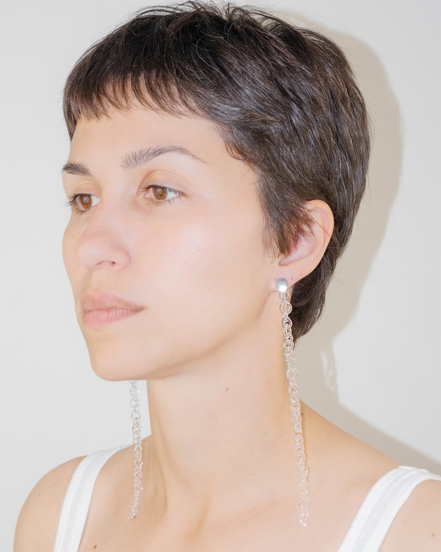 Model wearing Thin Chain Earrings, extra-long chain style handmade from borosilicate glass with orb top detail and sterling silver studs.